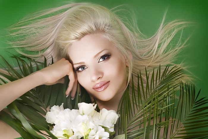 Blonde girl with flowers and palm leaves