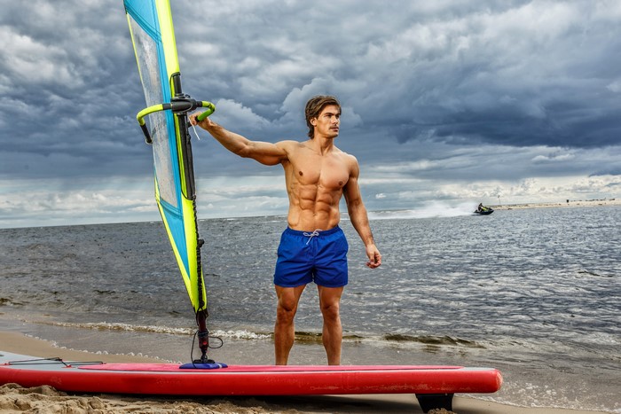 Man with windsurf board on the beach