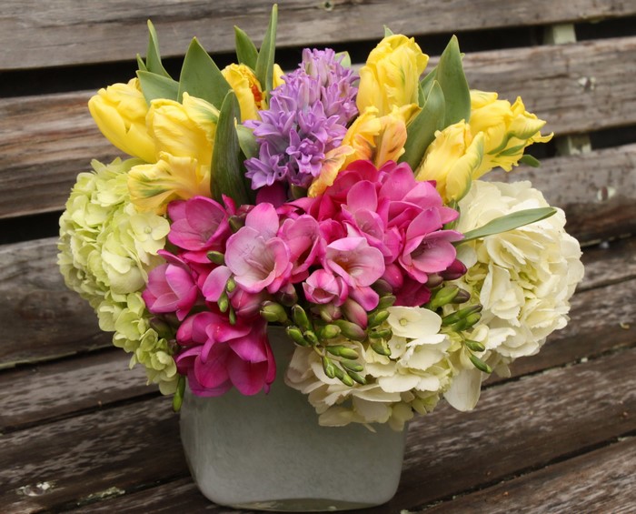 Yellow tulips, pink freesia, and purple hyacinths in a bouquet