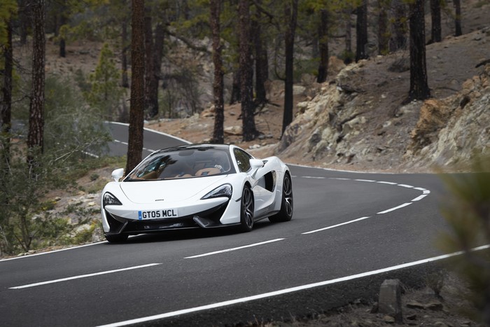 White McLaren 570GT driving on a mountain road