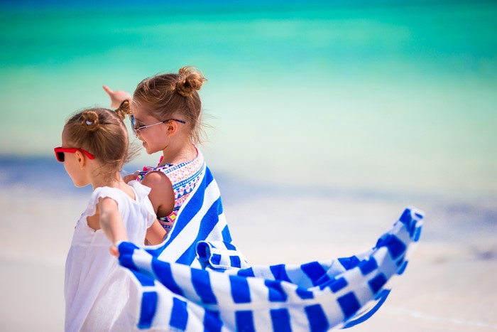 Two little girls on a beach with a towel