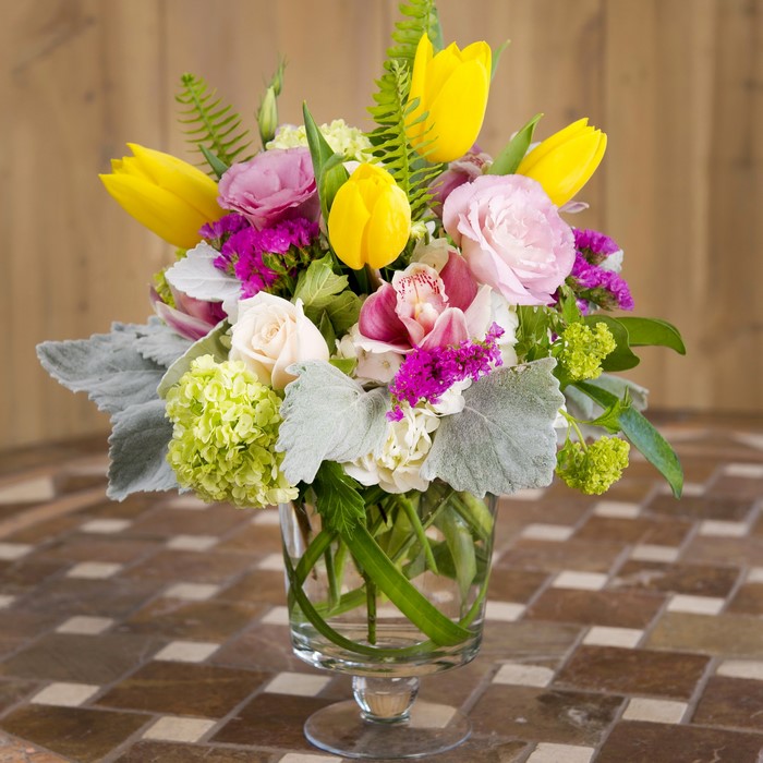 Yellow tulips and pink roses floral arrangement in a glass vase