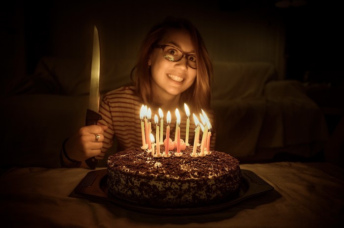 Woman holding a knife near a birthday cake with candles