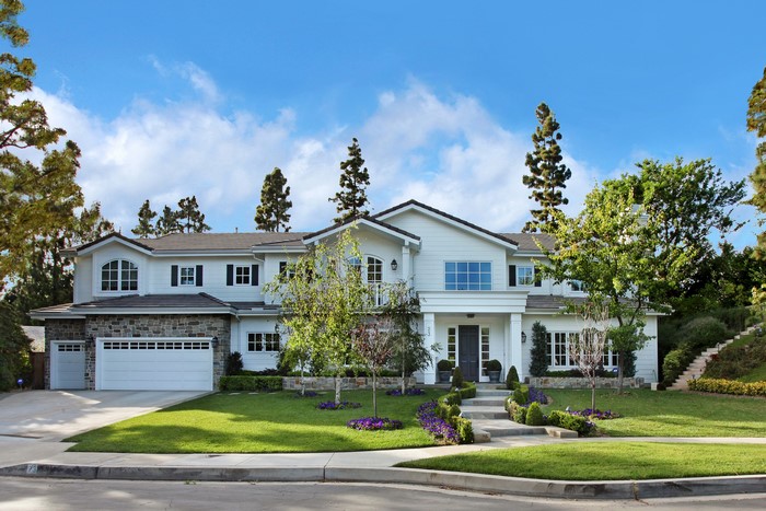 White modern house with stone accents and manicured lawn
