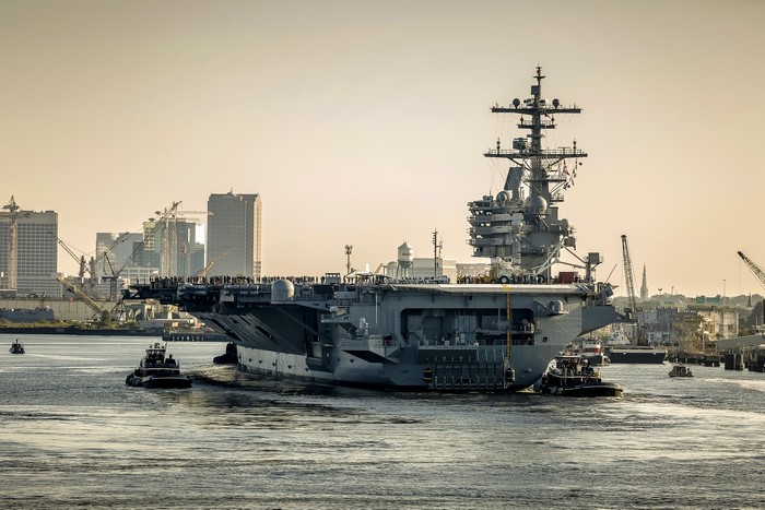 USS George H.W. Bush (CVN 77) aircraft carrier with tugboats