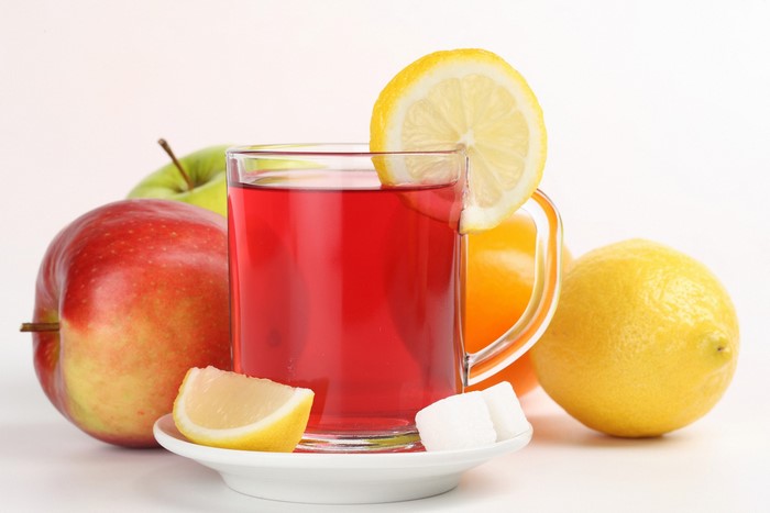 Glass of red tea with apples, lemons, and sugar cubes