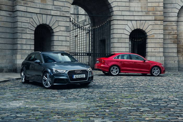 Two Audi A3 cars parked outside a stone building