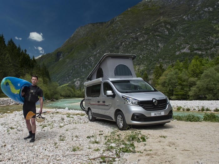 Man with kayak and Adria Active camper van by river