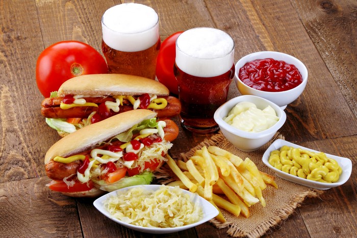 Hot dogs, French fries, and beer with condiments