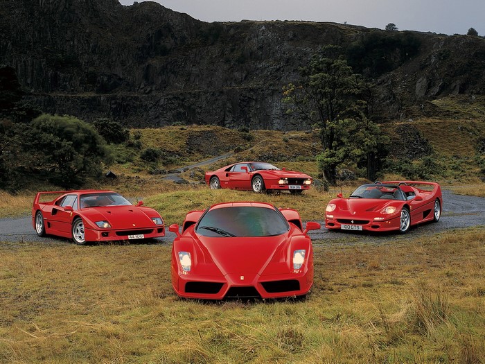 Four red Ferraris in a rocky landscape
