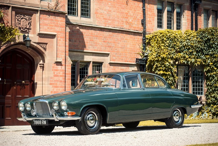 Green Jaguar Mark X parked in front of a brick building