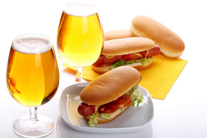 Two glasses of beer and hot dogs on a white background