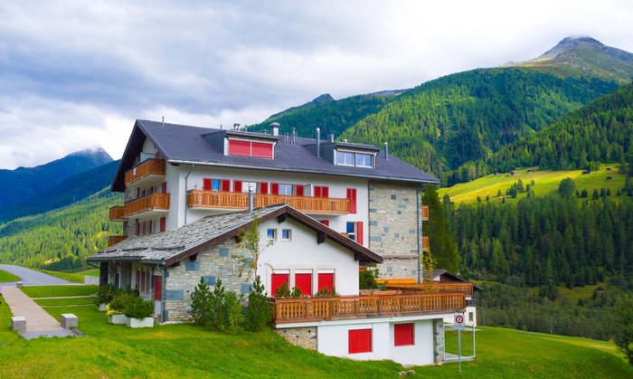 Alpine hotel building with mountains and forest in Switzerland
