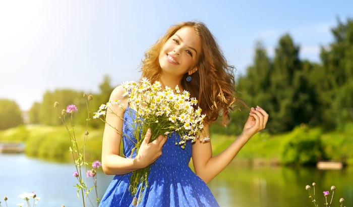 Young woman holding a bouquet of daisies by a lake