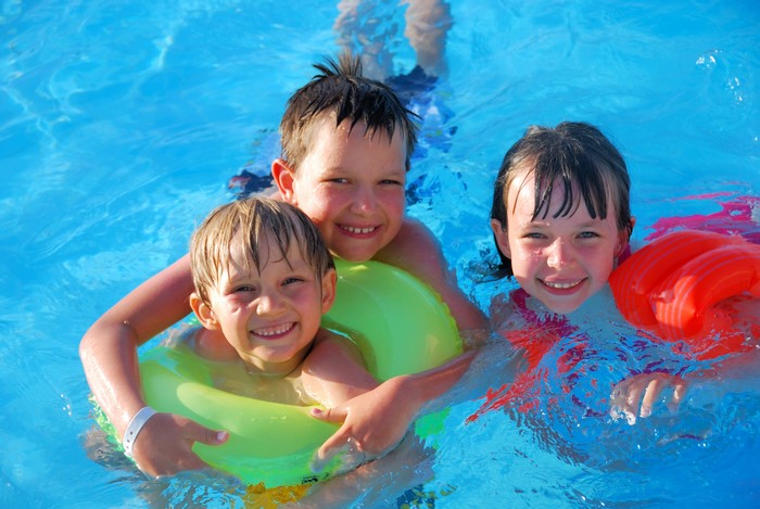 Three smiling children in a swimming pool