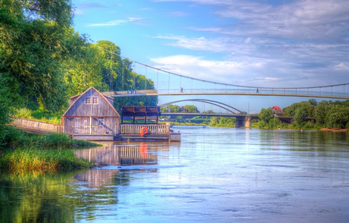 Wooden boathouse on a river with bridges in the background