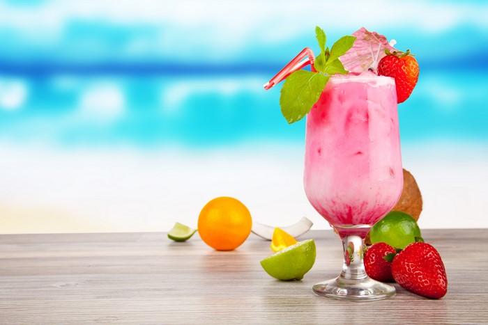 Pink Cocktail with Strawberries and Citrus Fruits on a Beach Background