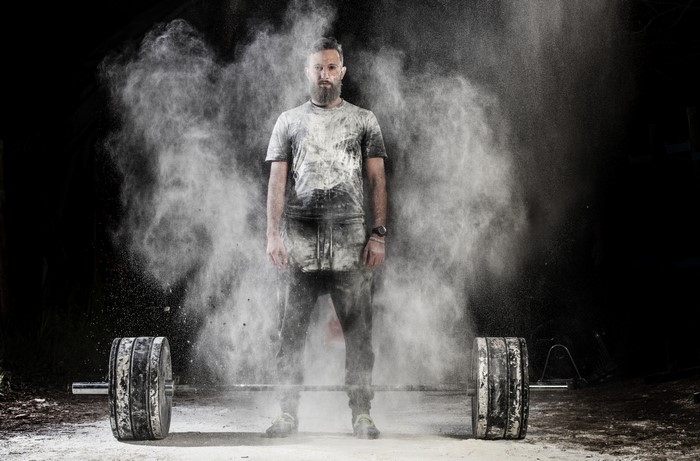 Man with barbell covered in chalk dust