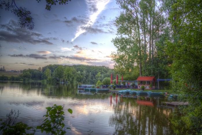 Boats docked at a lake marina with trees and sky