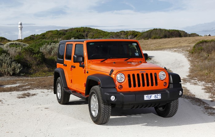Orange Jeep Wrangler Unlimited Sport on a dirt road