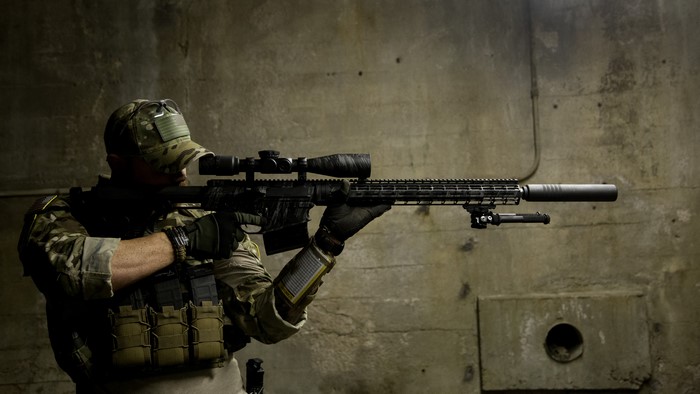 Soldier aiming a sniper rifle with suppressor