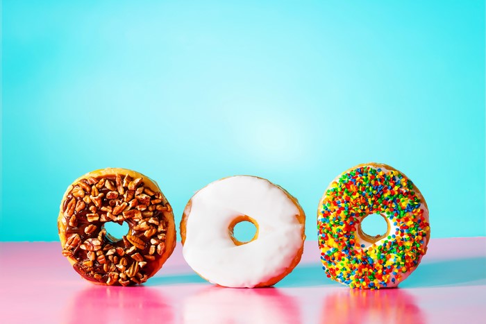 Three donuts on a pink and blue background