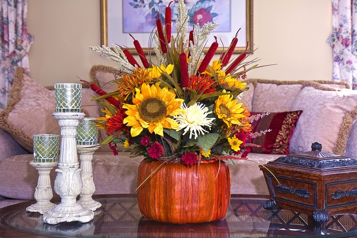 Autumn floral arrangement in a pumpkin vase with candles
