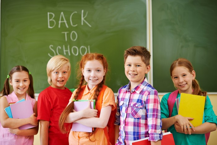 Children with books in front of a blackboard