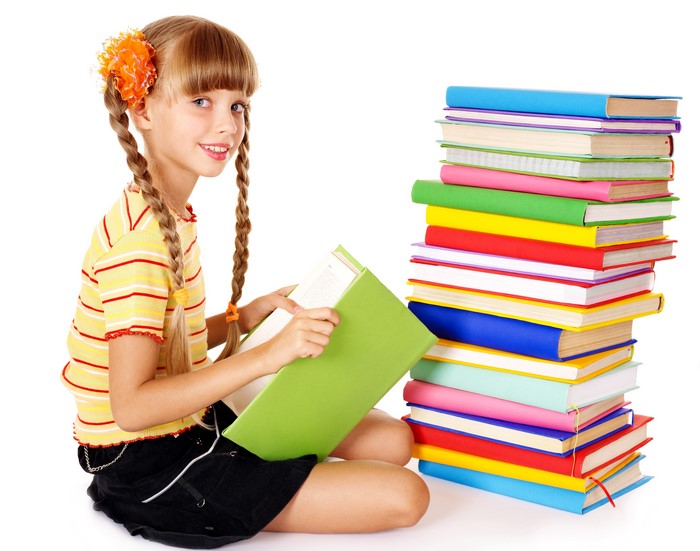 Smiling Girl Reading Book Sitting by Stack of Books 4K