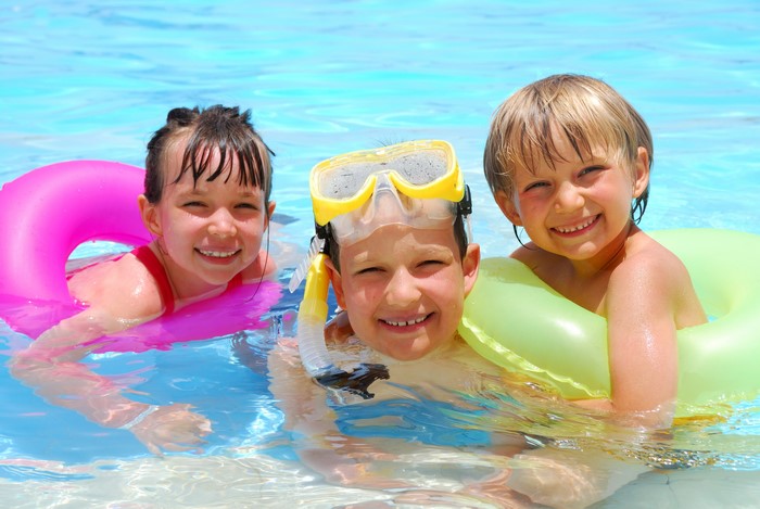 Three children in a swimming pool with inflatable rings