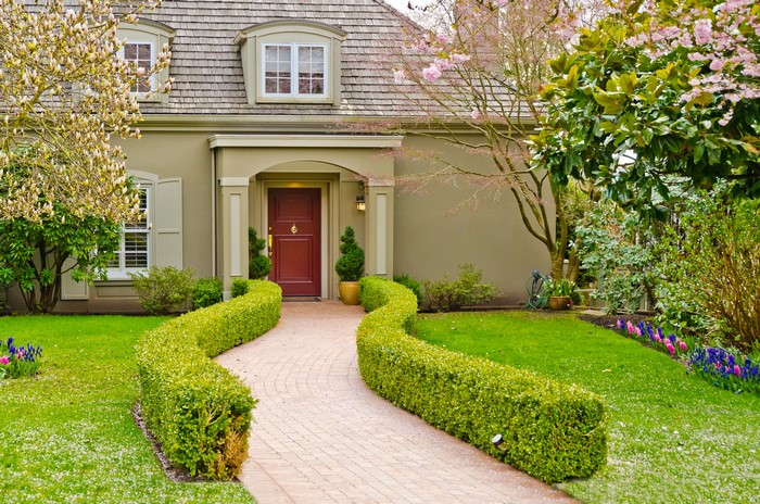 House with a winding brick pathway and manicured hedges
