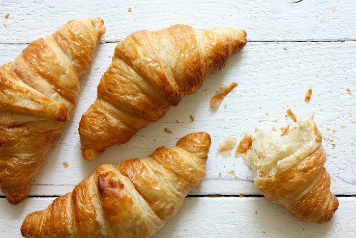 Four croissants on a white wooden table