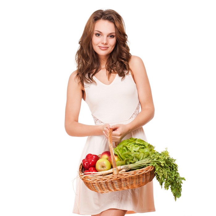 Woman holding a wicker basket with fruits and vegetables