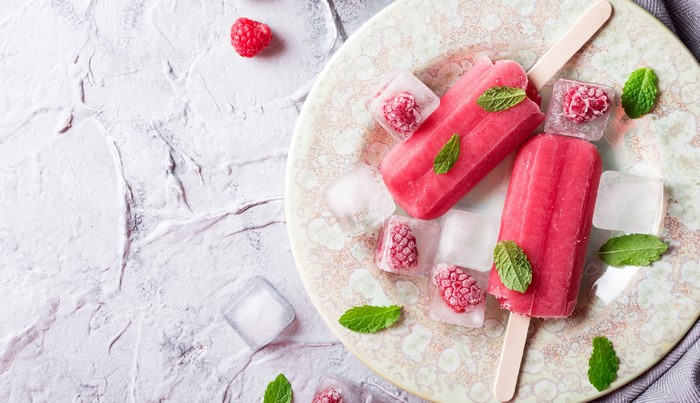 Raspberry popsicles with ice and mint on a plate