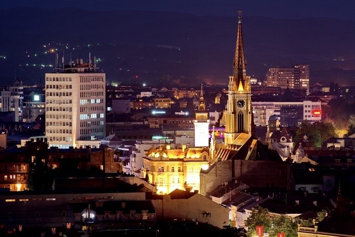 Novi Sad cityscape at night with church tower and modern building