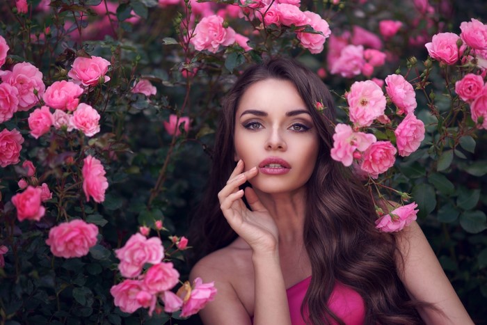 Woman with brown hair among pink roses
