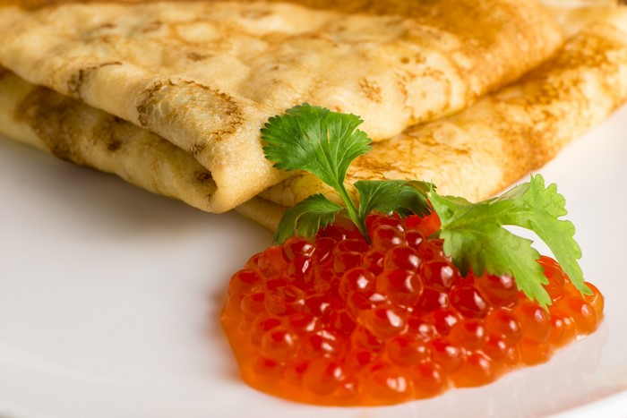 Pancakes with red caviar and parsley