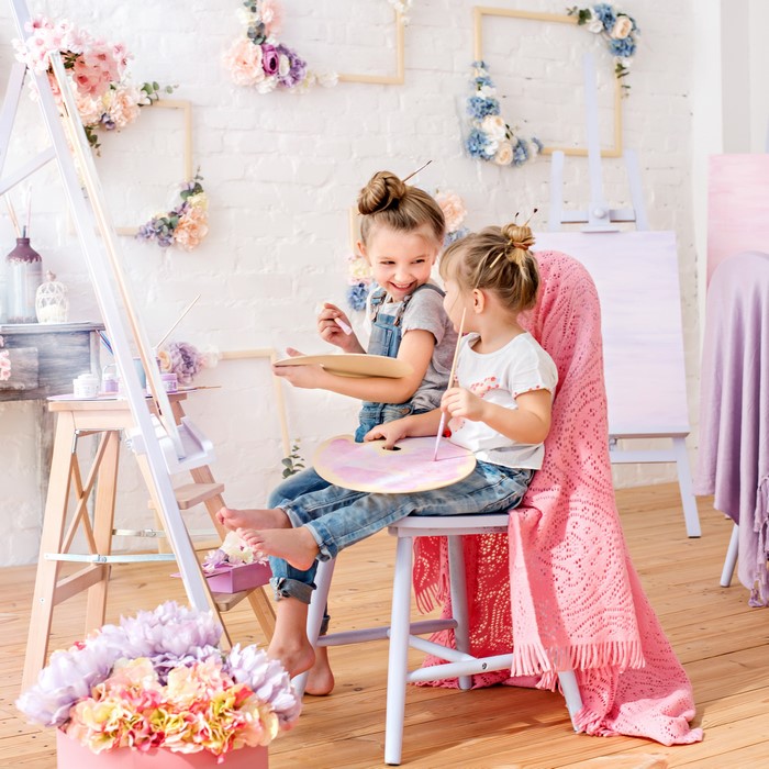 Two young girls painting at easels