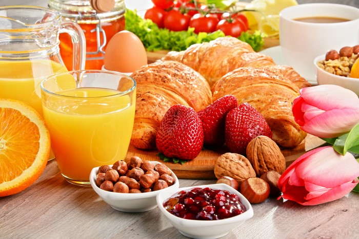 Breakfast still life with croissants, juice, strawberries, and tulips