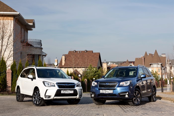Two Subaru Foresters in front of houses