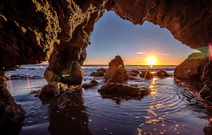 Sunset viewed from a cave entrance overlooking the ocean