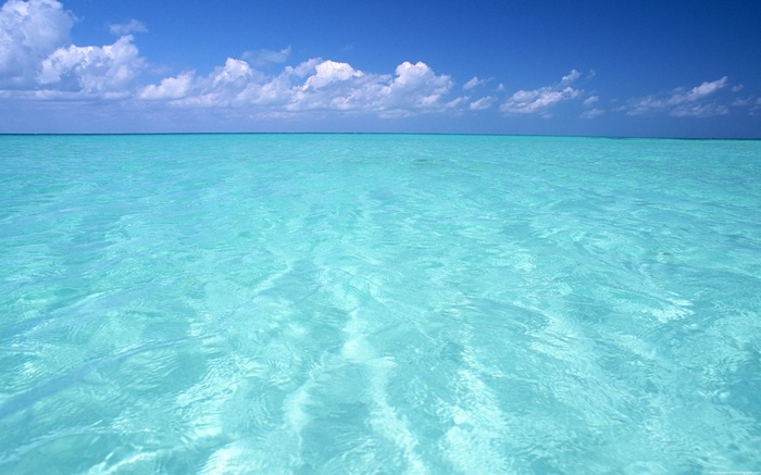 Turquoise ocean water under a blue sky with clouds