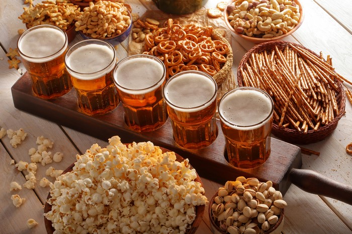 Beer glasses with pretzels, nuts, and popcorn