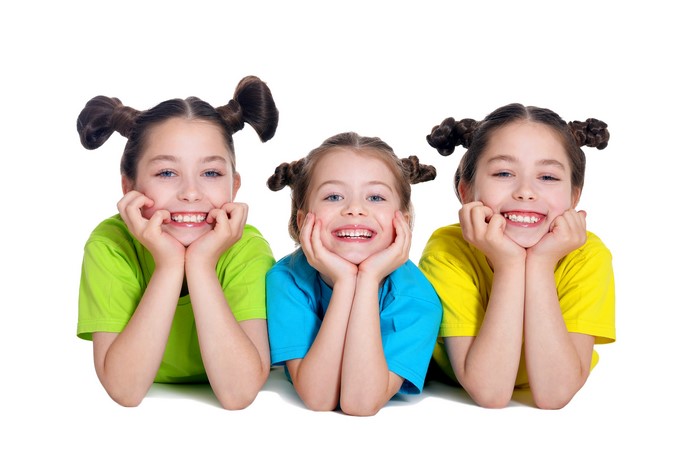 Three little girls with pigtails smiling on white background