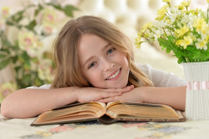 Smiling Little Girl Reading Book in Cozy Setting