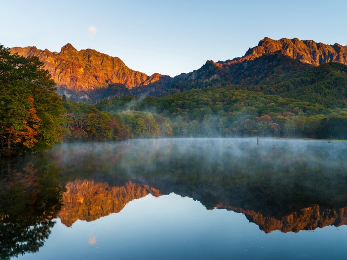 Mountains reflected in a misty lake at sunrise