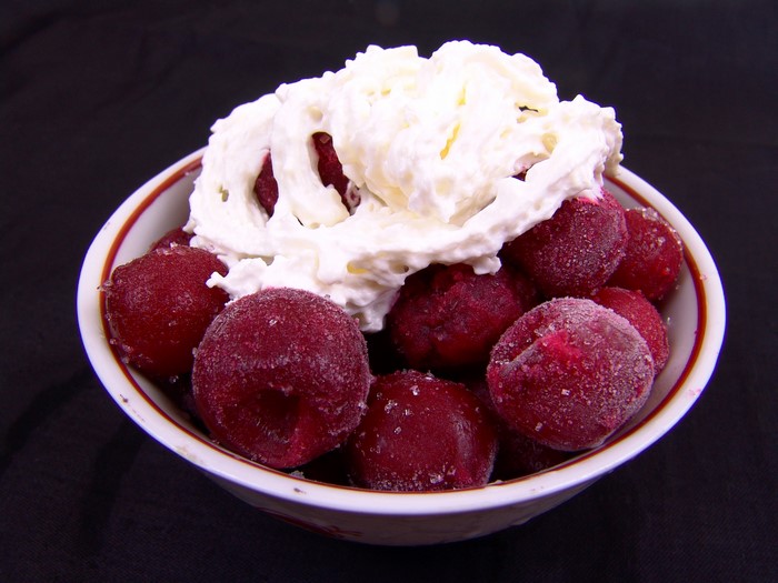 Frozen cherries with whipped cream in a bowl