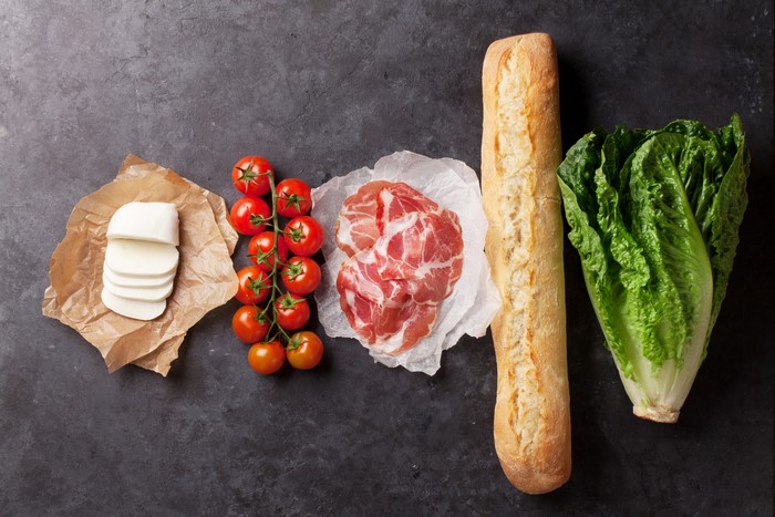 Ingredients for a sandwich: bread, cheese, ham, tomatoes, lettuce