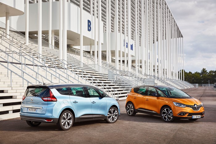 Two Renault Scenic cars in front of stadium stands