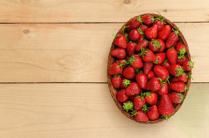Basket of fresh strawberries on a wooden table